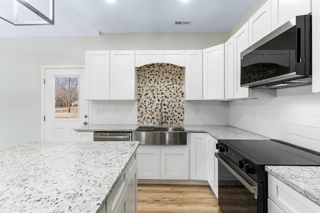 kitchen with stainless steel appliances, white cabinetry, light stone counters, and tasteful backsplash