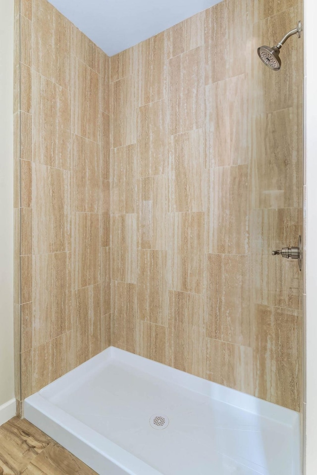 bathroom with hardwood / wood-style floors and a tile shower