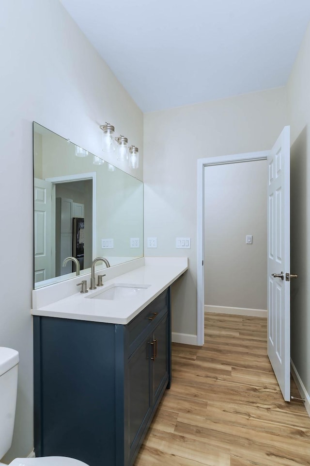 bathroom with vanity, toilet, and hardwood / wood-style floors