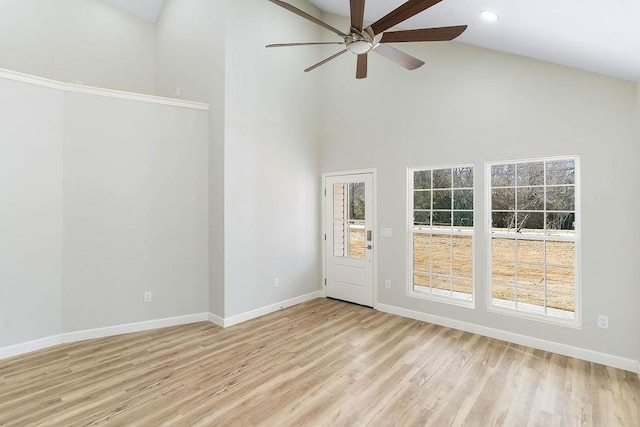 empty room with ceiling fan, high vaulted ceiling, and light hardwood / wood-style flooring