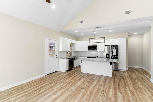 kitchen featuring stainless steel appliances, white cabinetry, a kitchen island, and tasteful backsplash