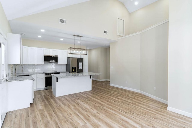 kitchen featuring a kitchen island, decorative light fixtures, white cabinetry, stainless steel appliances, and sink