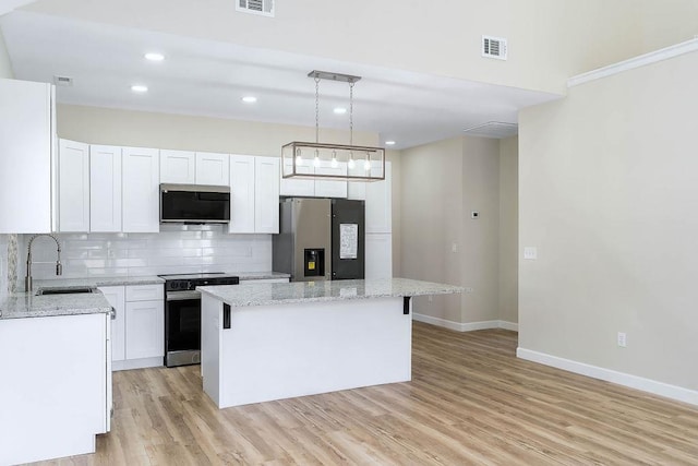 kitchen featuring white cabinets, appliances with stainless steel finishes, a center island, sink, and hanging light fixtures