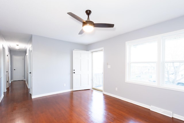 empty room featuring ceiling fan, a wealth of natural light, and dark hardwood / wood-style floors