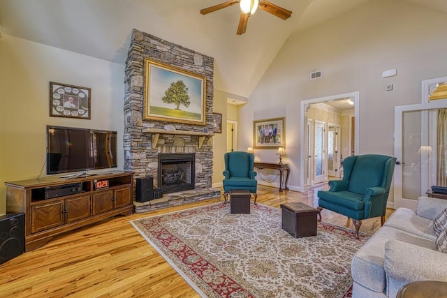 living room with a fireplace, light hardwood / wood-style flooring, high vaulted ceiling, and ceiling fan