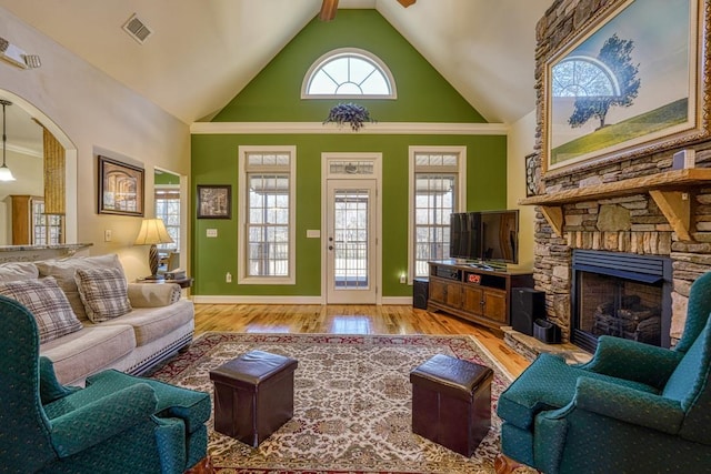 living room with beamed ceiling, light hardwood / wood-style flooring, a fireplace, and high vaulted ceiling