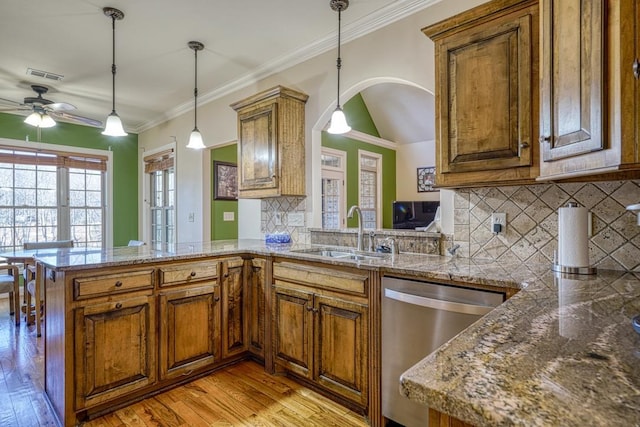 kitchen with kitchen peninsula, stainless steel dishwasher, pendant lighting, sink, and decorative backsplash