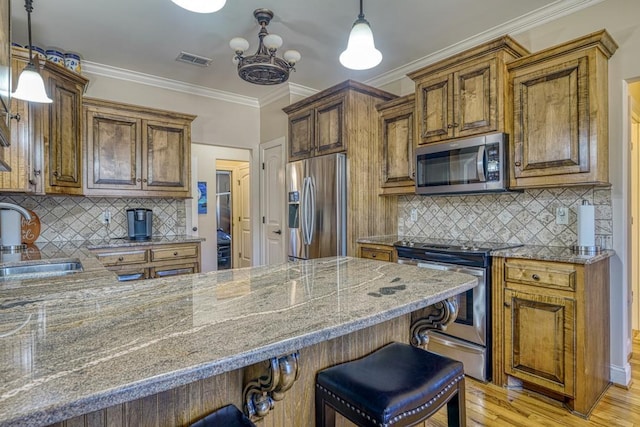 kitchen with a kitchen breakfast bar, pendant lighting, appliances with stainless steel finishes, sink, and decorative backsplash