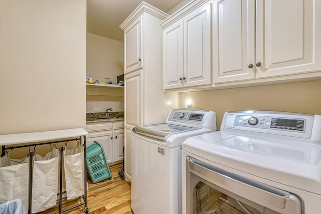 laundry area with light hardwood / wood-style floors, cabinets, sink, and independent washer and dryer