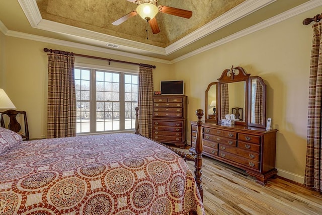 bedroom featuring ceiling fan, light hardwood / wood-style floors, crown molding, and a raised ceiling