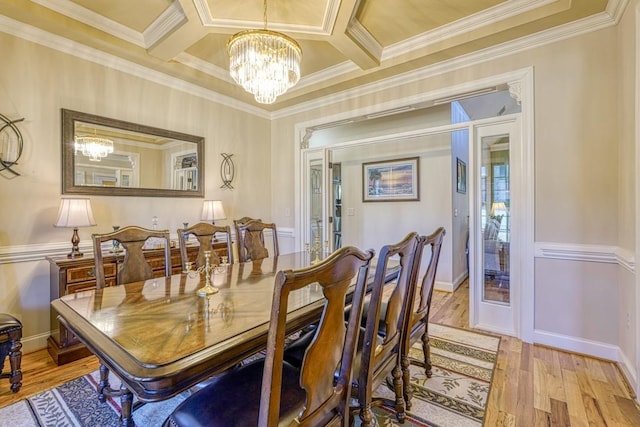 dining space featuring light hardwood / wood-style floors, coffered ceiling, crown molding, and an inviting chandelier