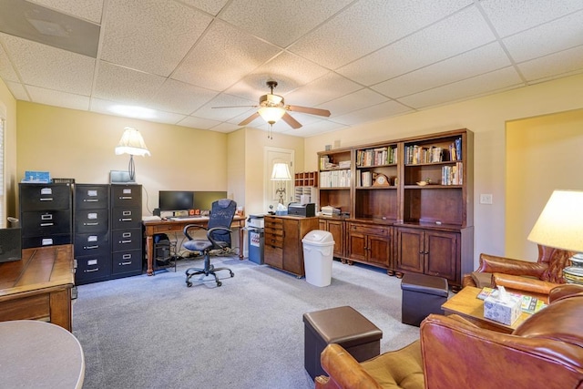 carpeted office space with ceiling fan and a paneled ceiling