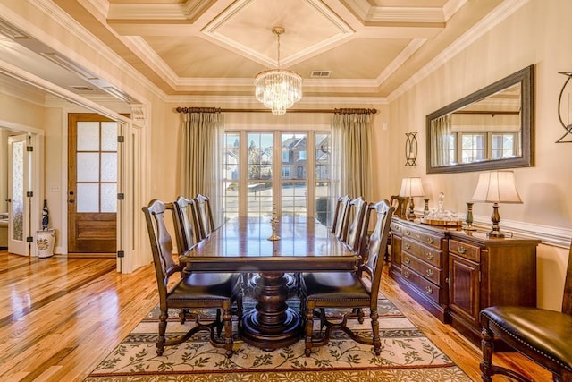 dining room featuring a notable chandelier, coffered ceiling, light hardwood / wood-style flooring, and ornamental molding