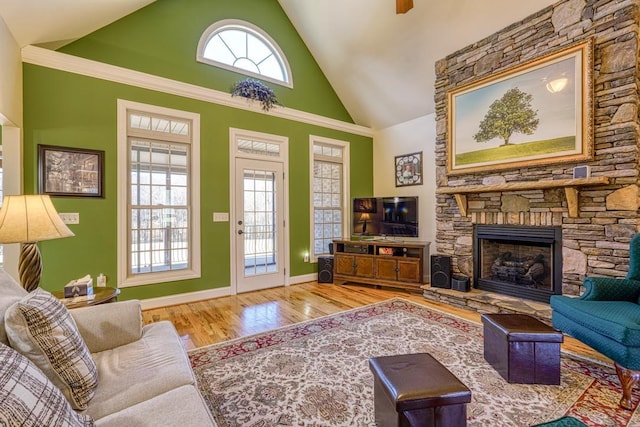 living room with high vaulted ceiling, hardwood / wood-style floors, and a stone fireplace