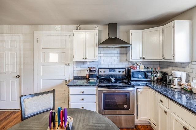 kitchen with appliances with stainless steel finishes, white cabinetry, backsplash, dark stone counters, and wall chimney exhaust hood