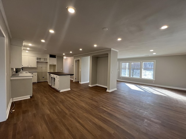 kitchen with dark wood-type flooring, white cabinetry, a center island, and crown molding