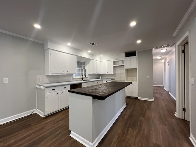 kitchen with dark hardwood / wood-style floors, backsplash, white cabinets, and a center island