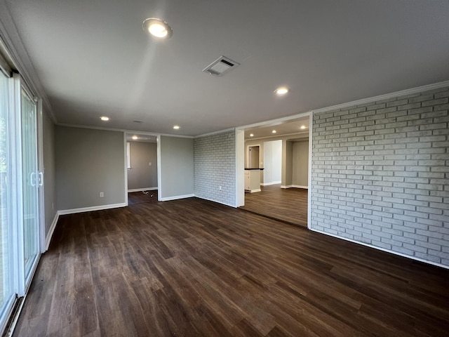 empty room with dark wood-type flooring, brick wall, and crown molding