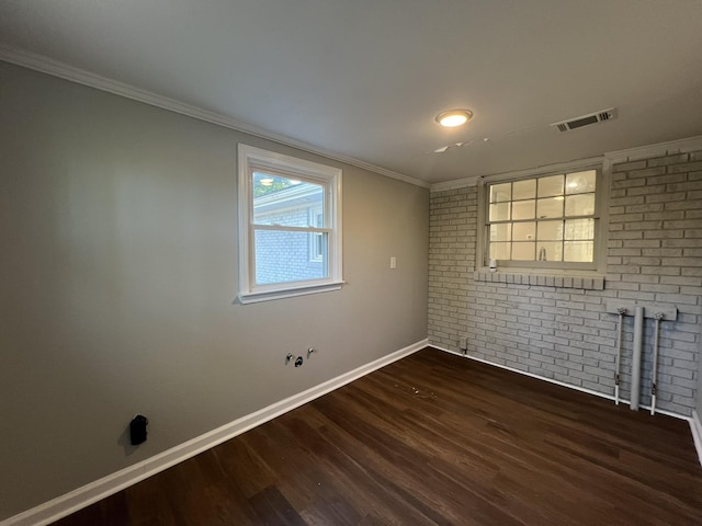 spare room featuring brick wall, ornamental molding, and dark hardwood / wood-style flooring