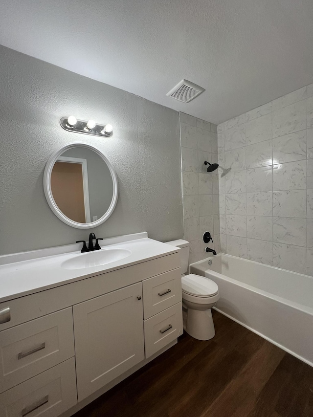 full bathroom featuring tiled shower / bath combo, hardwood / wood-style floors, toilet, a textured ceiling, and vanity