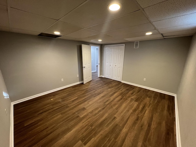 basement featuring a paneled ceiling and dark wood-type flooring