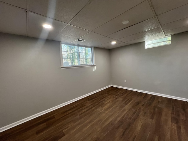 basement with a drop ceiling and dark hardwood / wood-style flooring