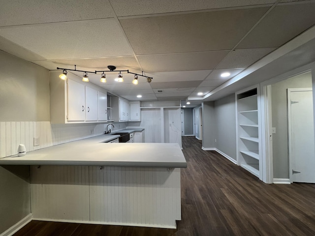 kitchen featuring kitchen peninsula, dark wood-type flooring, white cabinetry, and a paneled ceiling