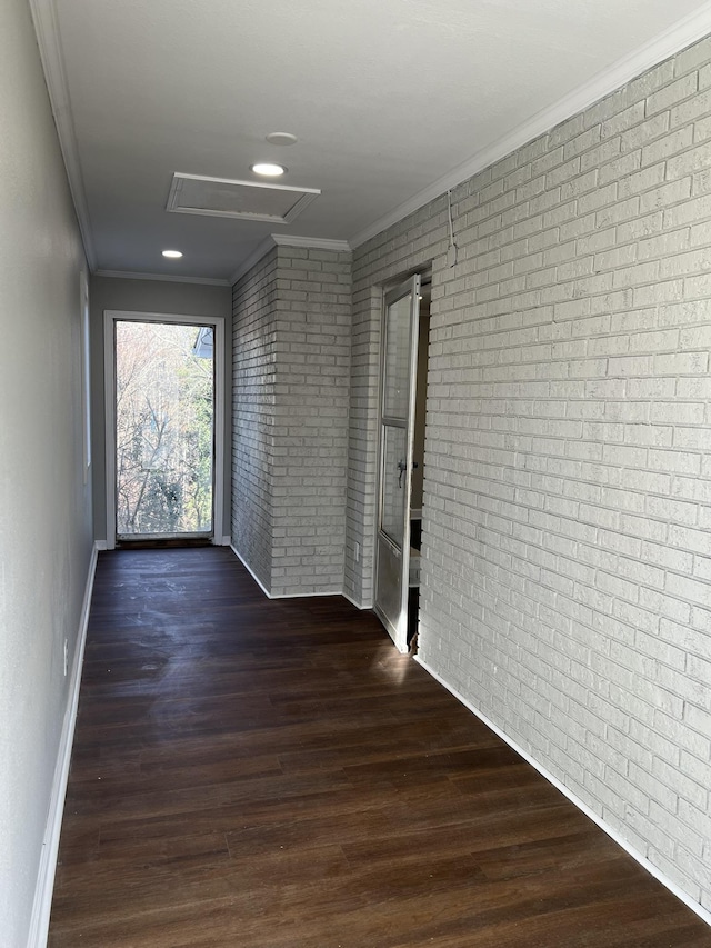 corridor featuring brick wall, crown molding, and dark wood-type flooring