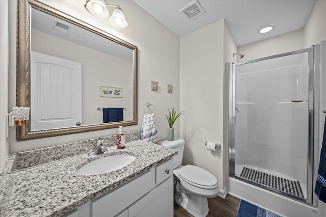 bathroom with hardwood / wood-style flooring, an enclosed shower, vanity, and toilet