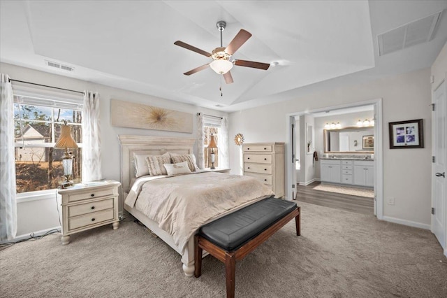 carpeted bedroom featuring multiple windows, vaulted ceiling, ensuite bath, and ceiling fan