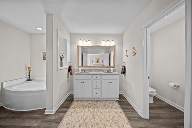 bathroom featuring vanity, toilet, a tub, and wood-type flooring