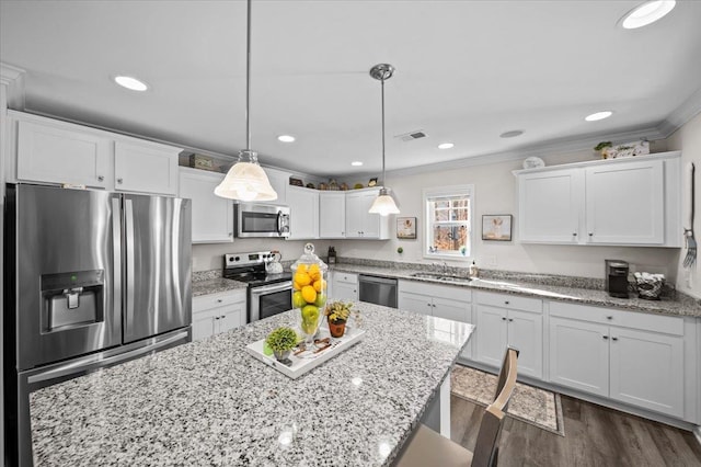 kitchen featuring white cabinets, appliances with stainless steel finishes, decorative light fixtures, dark hardwood / wood-style flooring, and ornamental molding