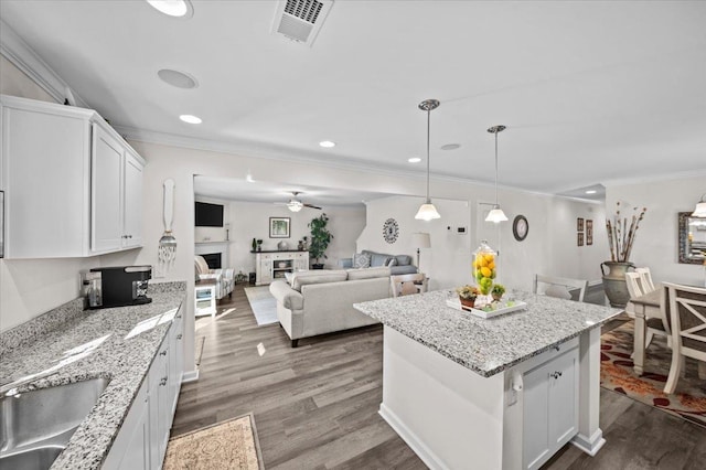 kitchen featuring pendant lighting, a center island, wood-type flooring, white cabinetry, and sink