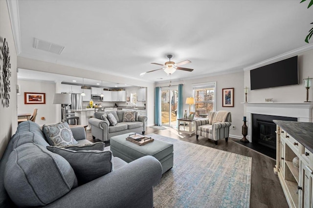 living room featuring ceiling fan, dark wood-type flooring, and crown molding