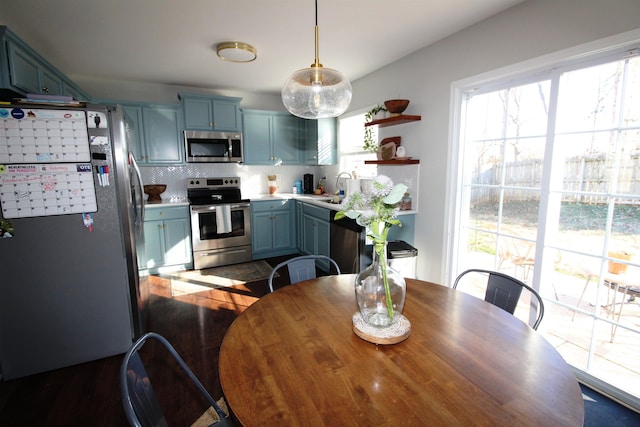 kitchen featuring hanging light fixtures, appliances with stainless steel finishes, sink, blue cabinetry, and tasteful backsplash