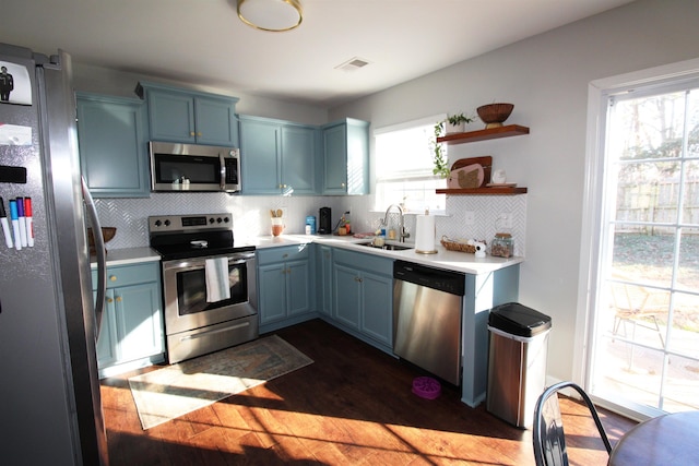 kitchen with sink, stainless steel appliances, blue cabinetry, and backsplash