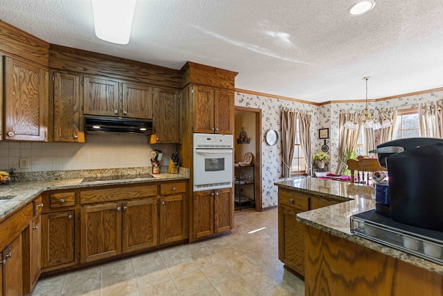 kitchen featuring pendant lighting, black electric cooktop, light stone countertops, white oven, and a textured ceiling