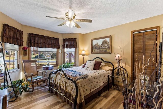 bedroom featuring a textured ceiling, ceiling fan, and light hardwood / wood-style floors