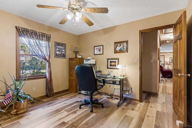 office space with ceiling fan, a textured ceiling, and light wood-type flooring