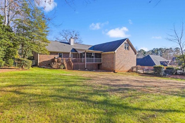 back of property featuring a wooden deck, a yard, and a sunroom