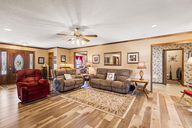 living room featuring crown molding, ceiling fan, a textured ceiling, and light hardwood / wood-style floors