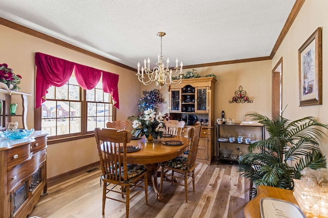 dining area with hardwood / wood-style flooring, ornamental molding, a textured ceiling, and an inviting chandelier