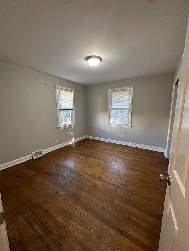 unfurnished room with dark wood-type flooring