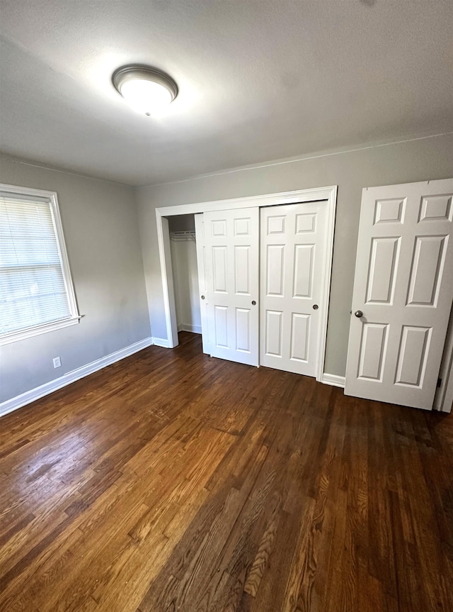 unfurnished bedroom featuring a closet and dark wood-type flooring