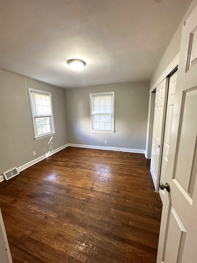 unfurnished bedroom featuring a closet and dark hardwood / wood-style floors