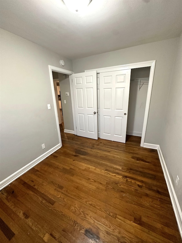 unfurnished bedroom featuring dark wood-type flooring and a closet