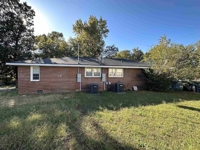 back of property with central AC and a yard