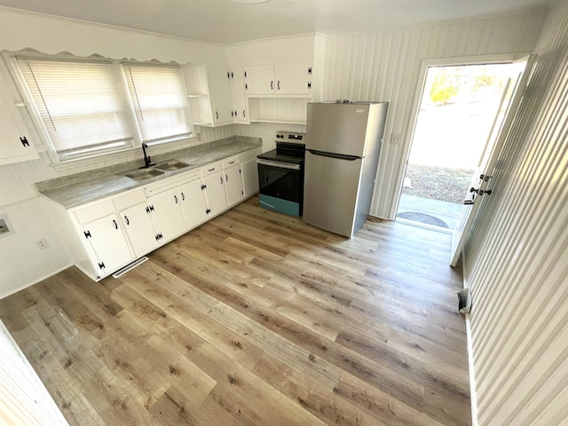 kitchen with appliances with stainless steel finishes, white cabinetry, sink, ornamental molding, and light hardwood / wood-style flooring