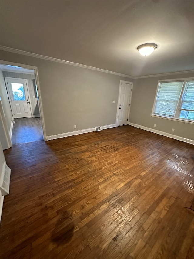 empty room featuring plenty of natural light, dark hardwood / wood-style flooring, and ornamental molding