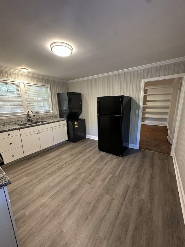 kitchen featuring sink, white cabinetry, black fridge, and dark stone counters